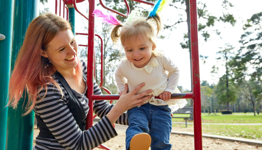 A mother practicing speech therapy strategies with her daughter at the playground.