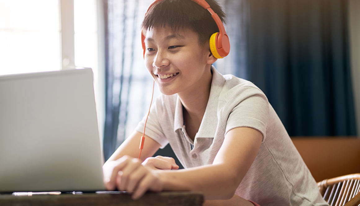 A teenage boy participating in virtual speech therapy using his laptop.