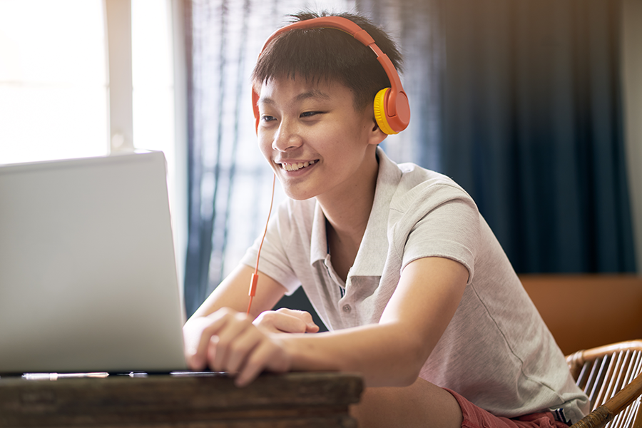 A teenage boy participating in virtual speech therapy using his laptop.