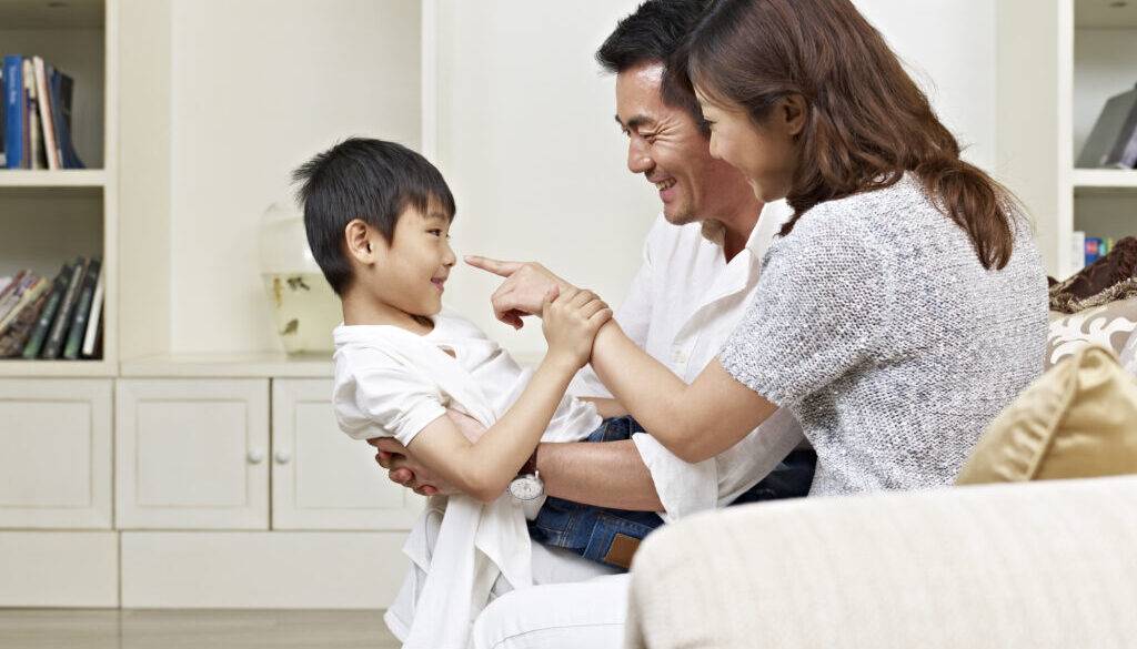 Two parents playing with their child and practicing speech sounds.