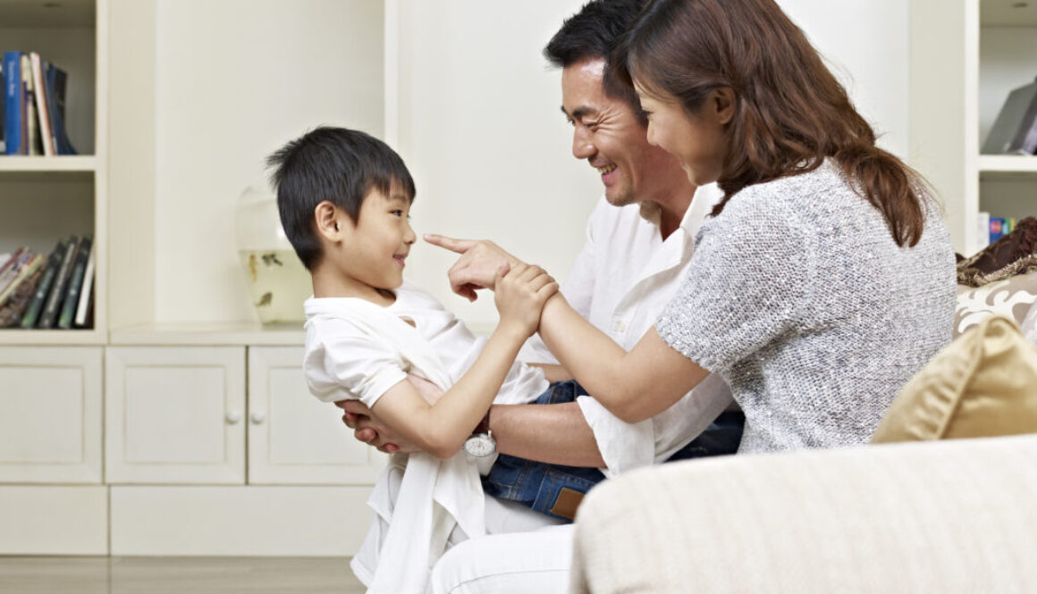 Two parents playing with their child and practicing speech sounds.