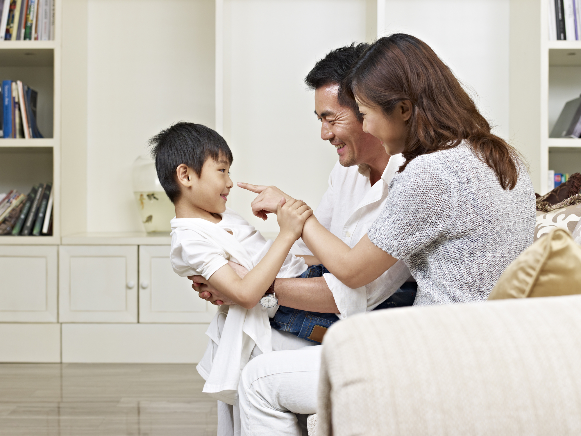 Two parents playing with their child and practicing speech sounds.