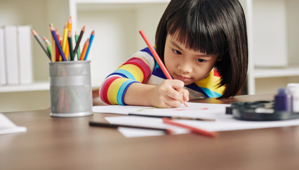 A speech pathologist helps a child complete schoolwork.