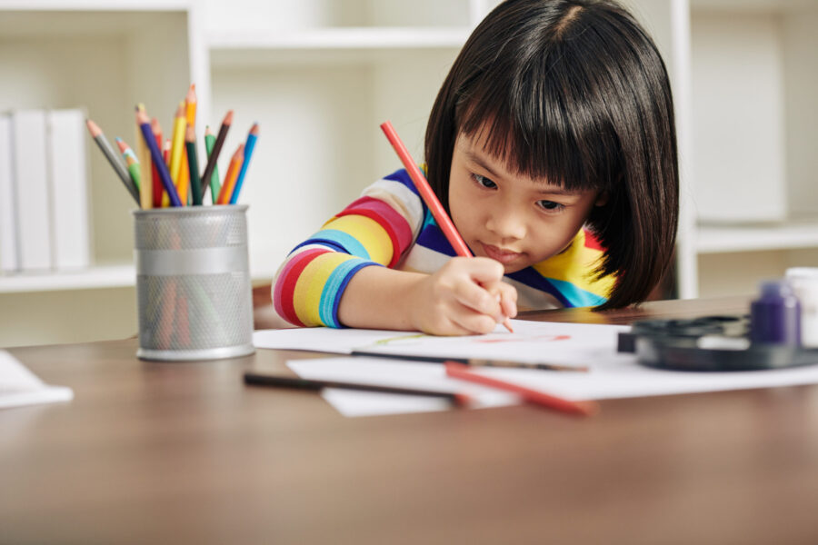 A speech pathologist helps a child complete schoolwork.