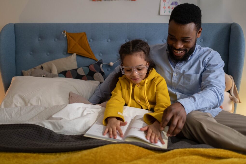 A parent reading to his child so that she learns more new words.