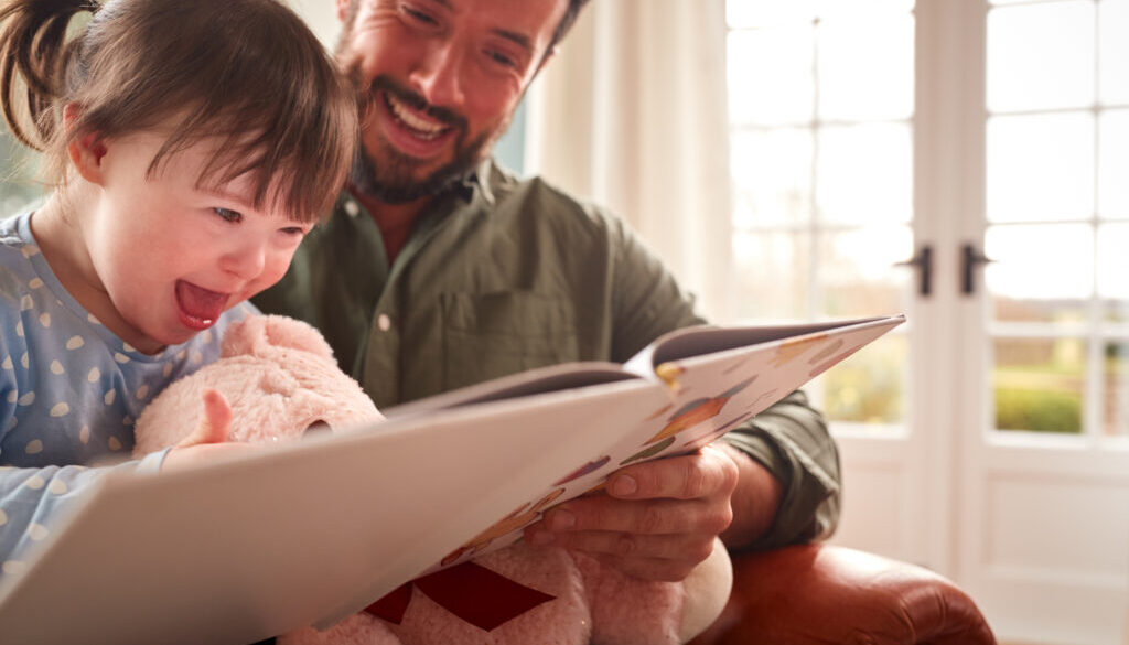 A father reads to his daughter with Down syndrome to help language therapy.