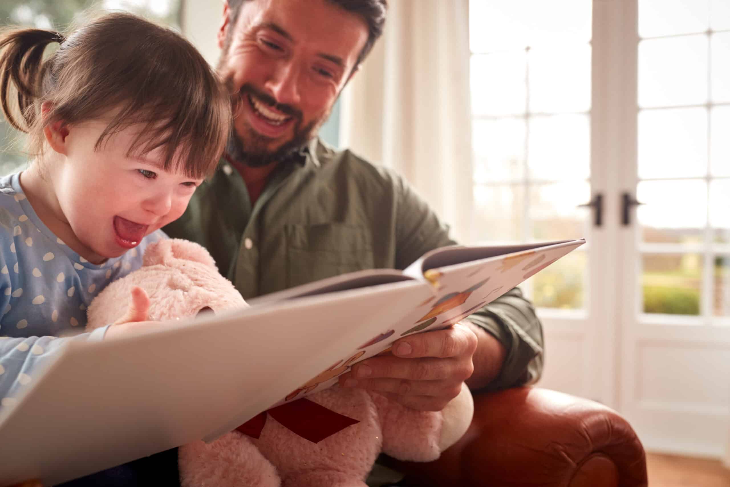 A father reads to his daughter with Down syndrome to help language therapy.