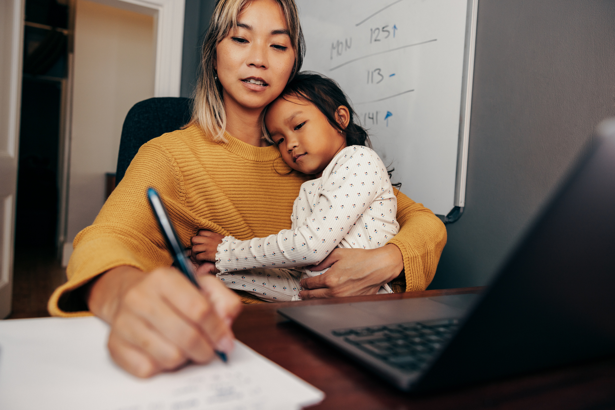 A mother talking to a speech therapist and taking notes.